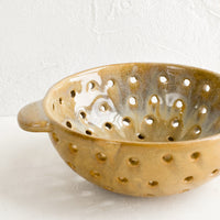 1: A round brown ceramic berry colander bowl.