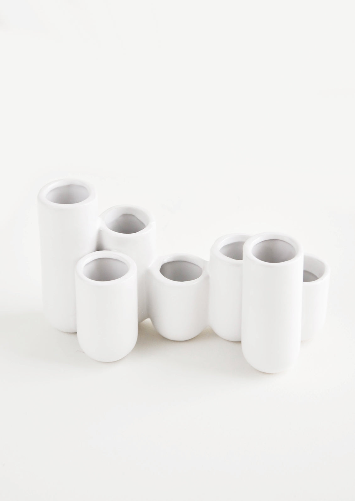 Multiple stem vase made of white ceramic vials in varying heights, clustered and fused together