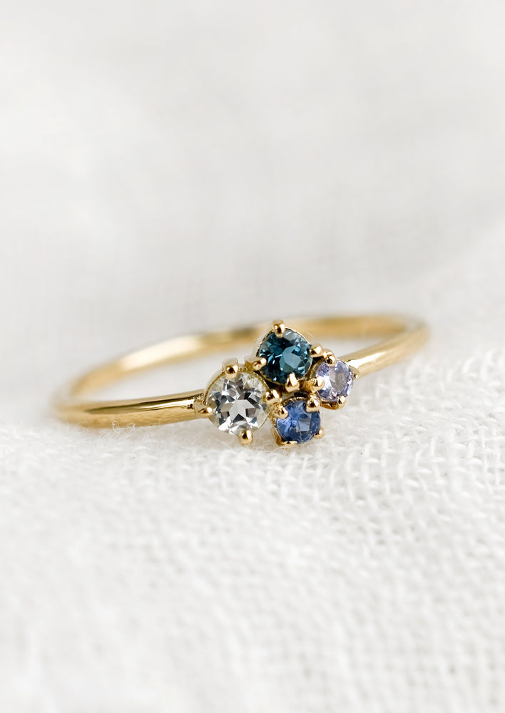 1: A gold ring with cluster of four gemstones in different shades of blue.