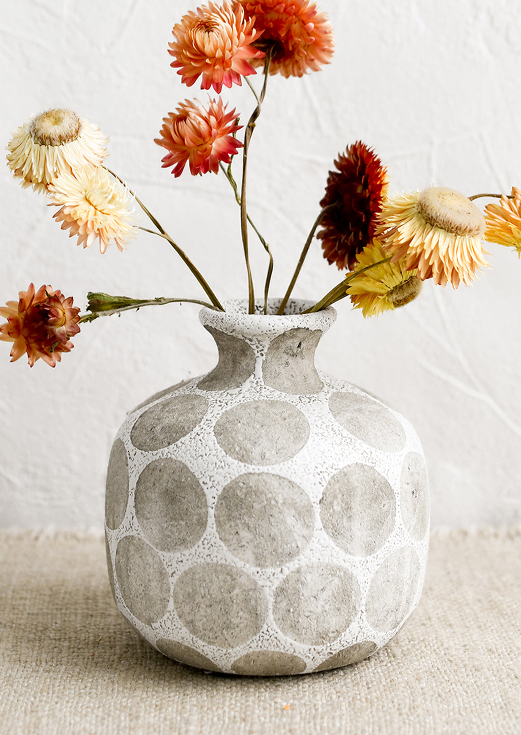 White Multi: A round vase with narrow neck, in white with grey polka dot print.