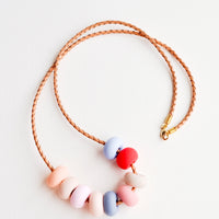 Desert Rose: Woven leather cord necklace with gold clasp and rounded clay beads tans, pinks, red, and blues.