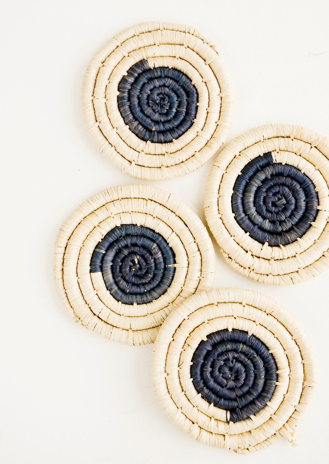 Set of four round raffia coasters with natural rim and charcoal colored center