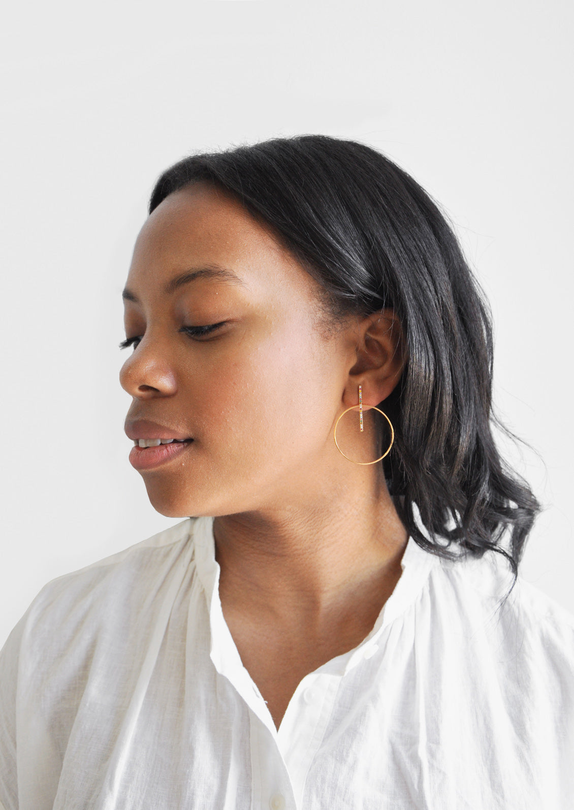 Model wearing colored crystal hoop earrings