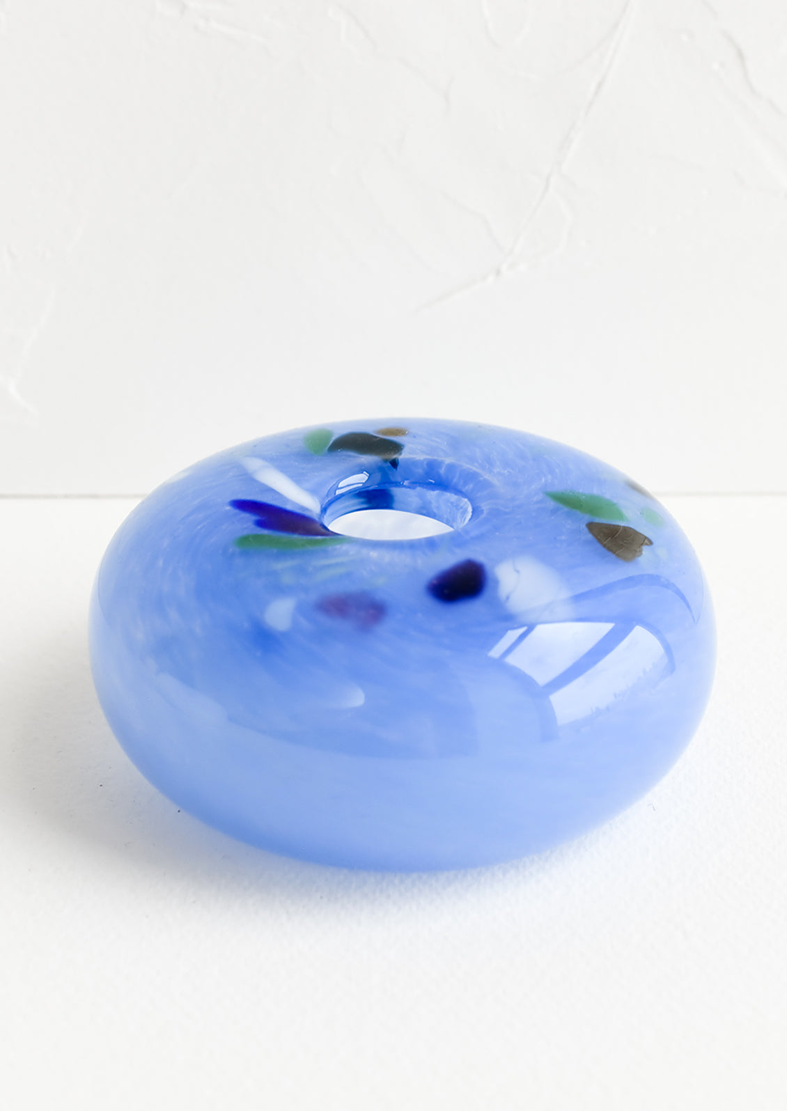A glass bud vase in blue with colorful fleck detail around opening.