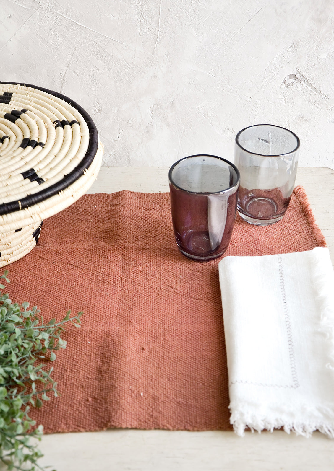 Table setting in earthy color palette with placemat, napkins and glass cups