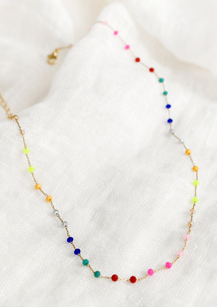 1: A beaded necklace with evenly spaced, rainbow gradient beads on gold chain.