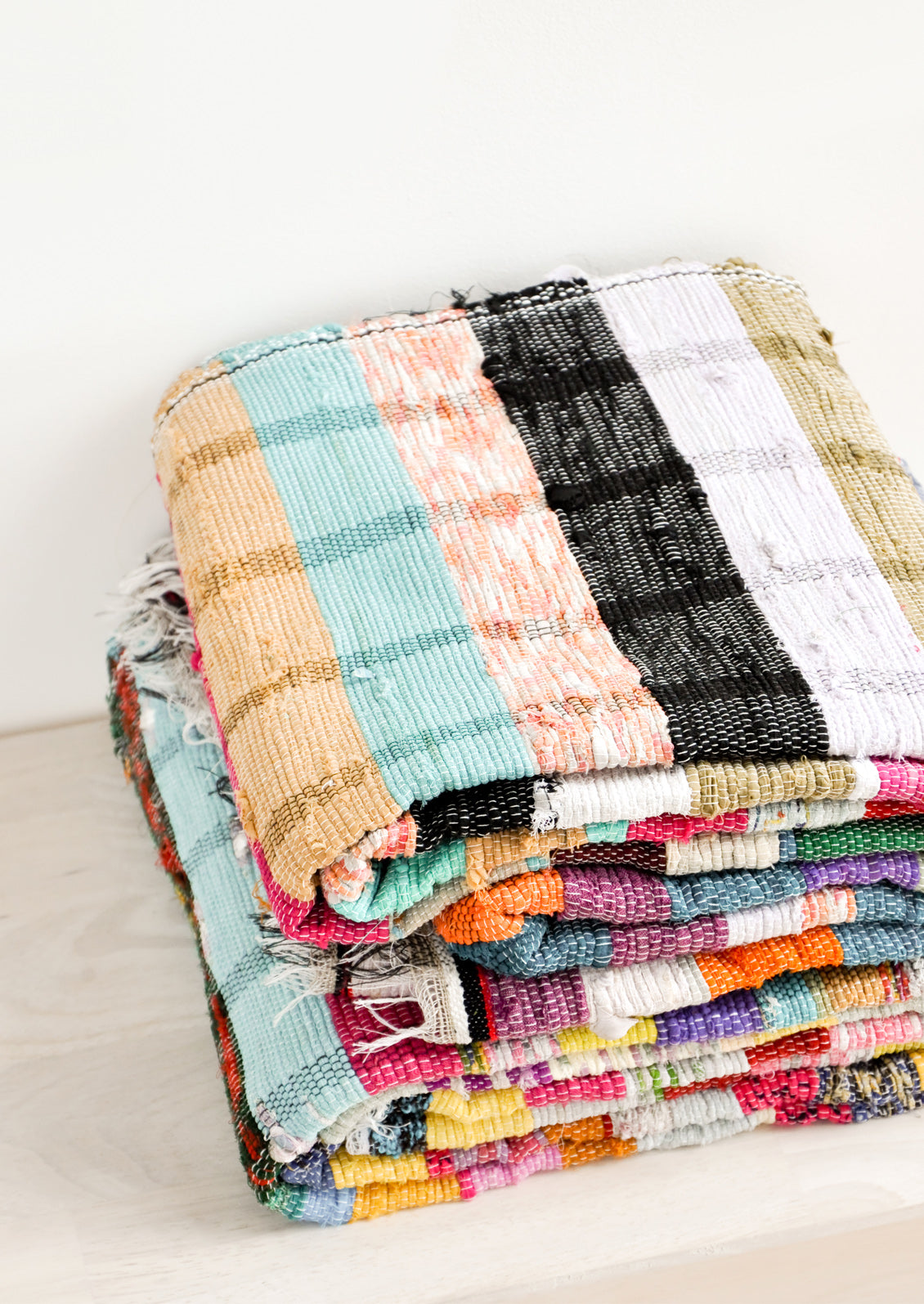 Stack of recycled cotton floor blankets in colorful stripes