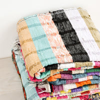 2: Stack of recycled cotton floor blankets in colorful stripes