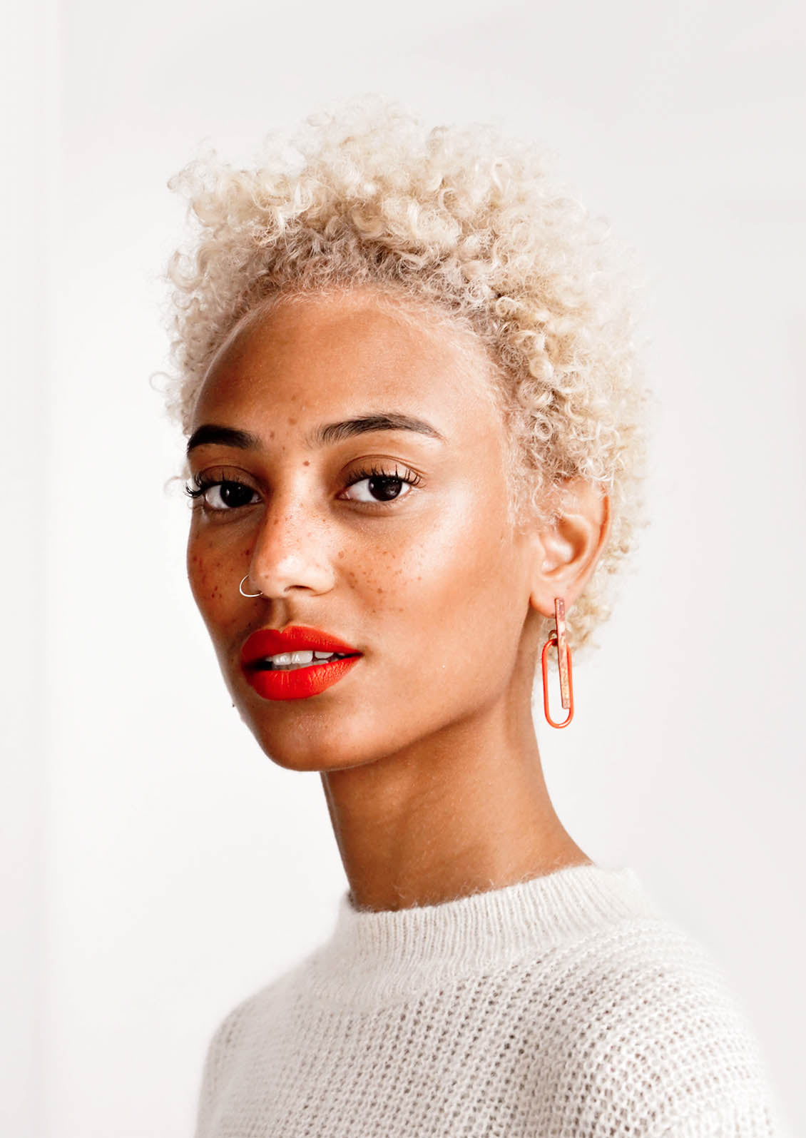 Model wearing sculptural brass and enamel earrings