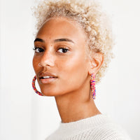2: Model wears multicolored beaded hoop earrings and white sweater.