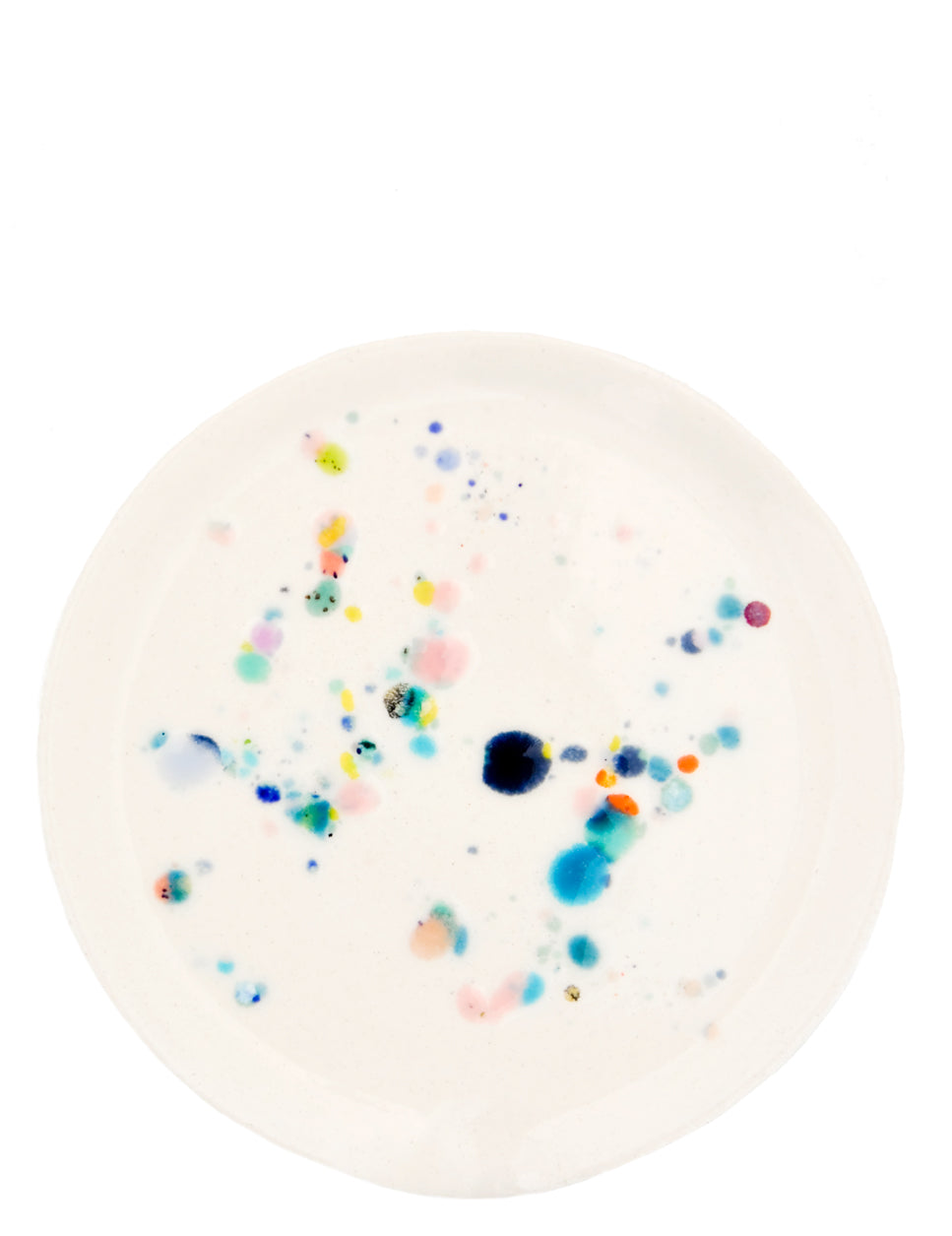 A round ceramic spoon rest with random, colorful glaze drips.