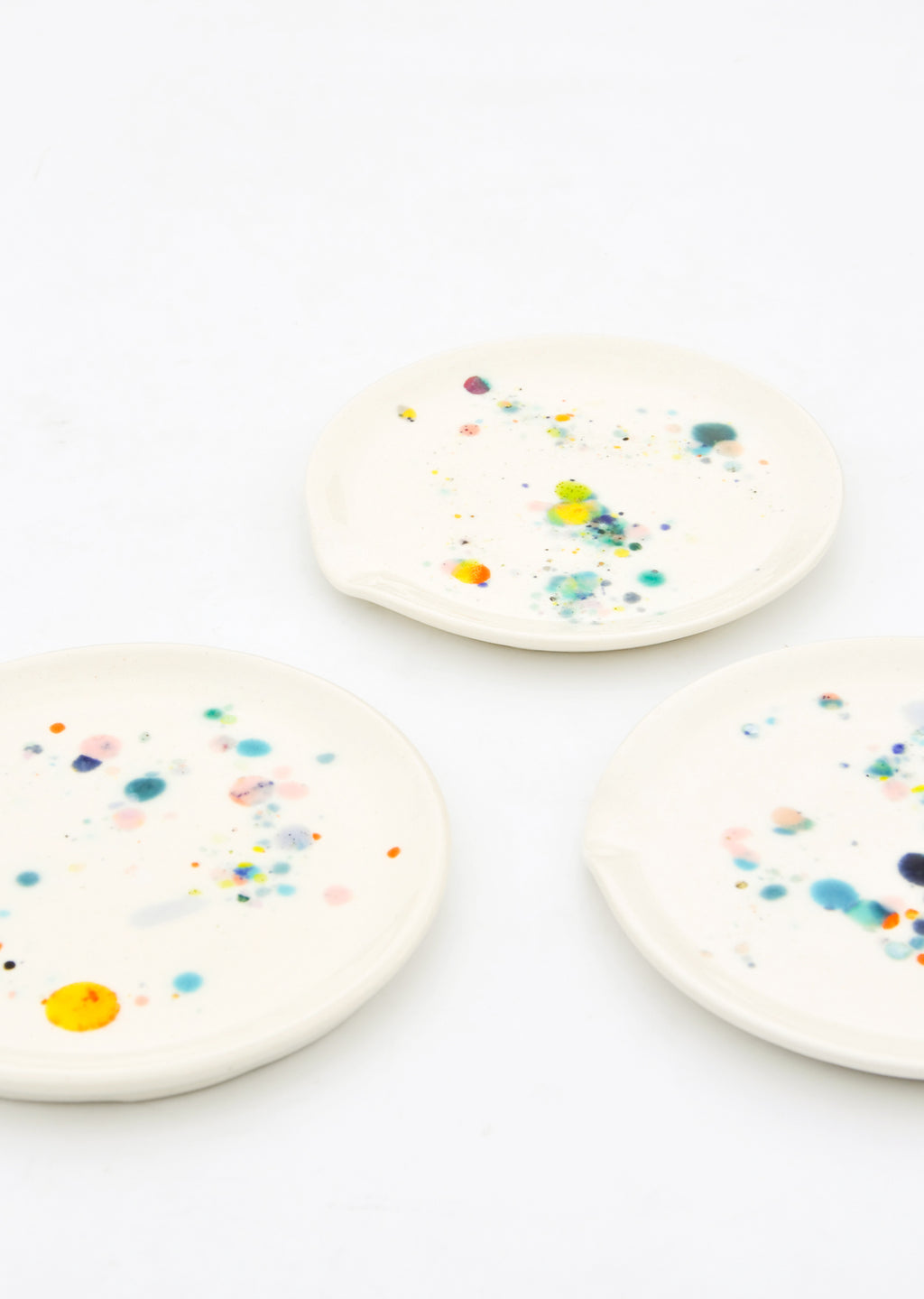 2: Three ceramic spoon rests in ivory with splattered colorful glaze drips.
