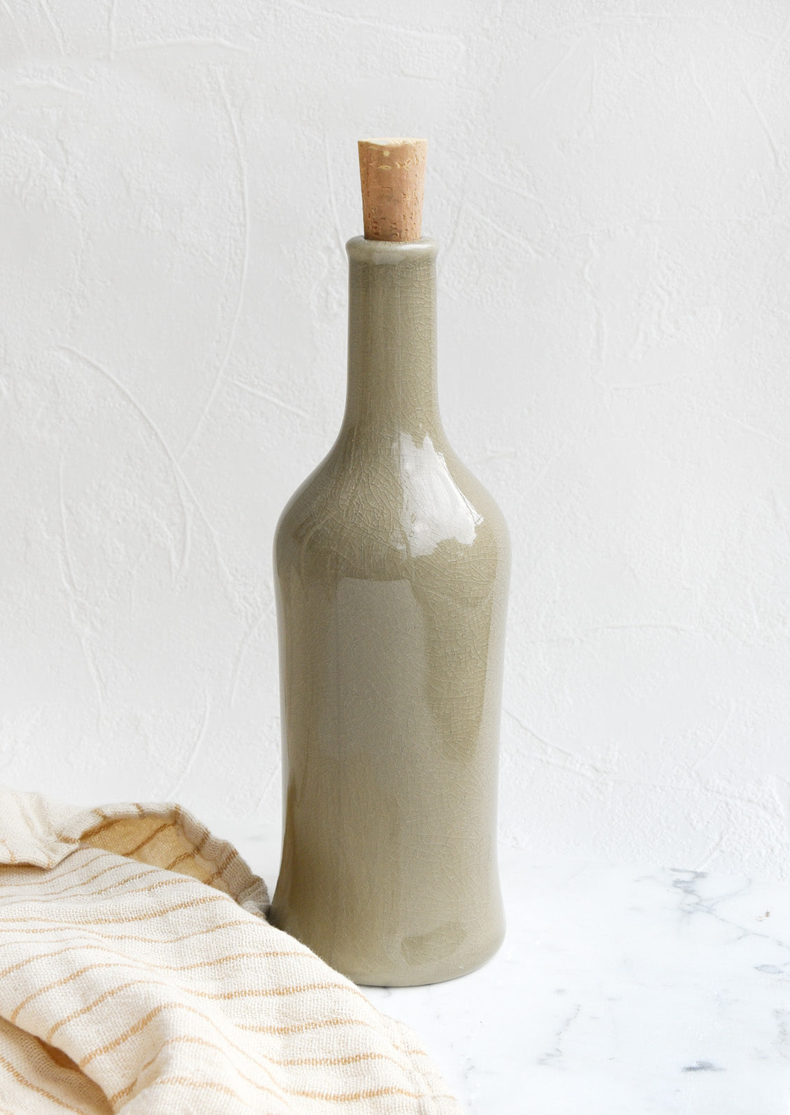 A glossy olive colored tall bottle with cork top