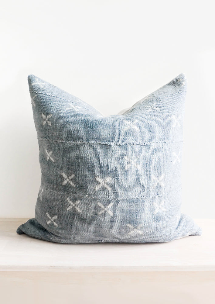 1: Square throw pillow in faded blue fabric with white X print throughout