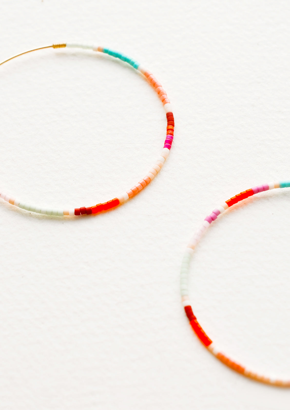 Close up detail of multi-colored beaded hoop earrings.