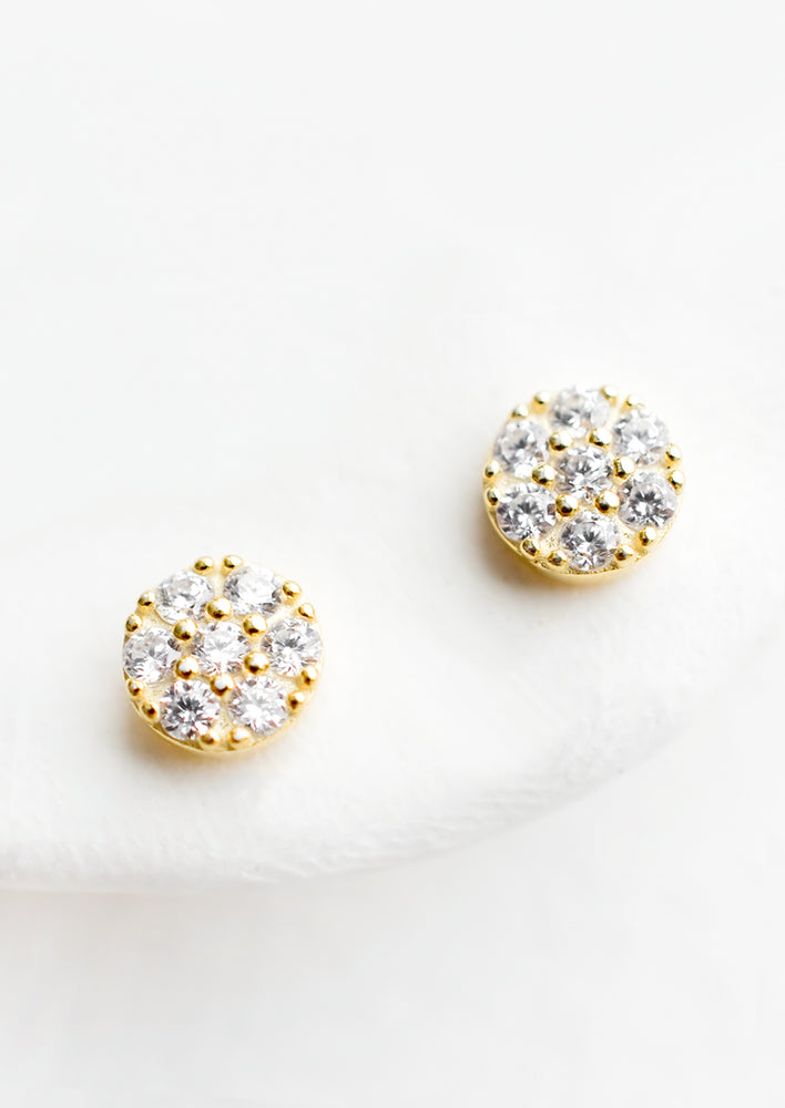 1: A pair of small gold circular studs with clear crystal detailing.