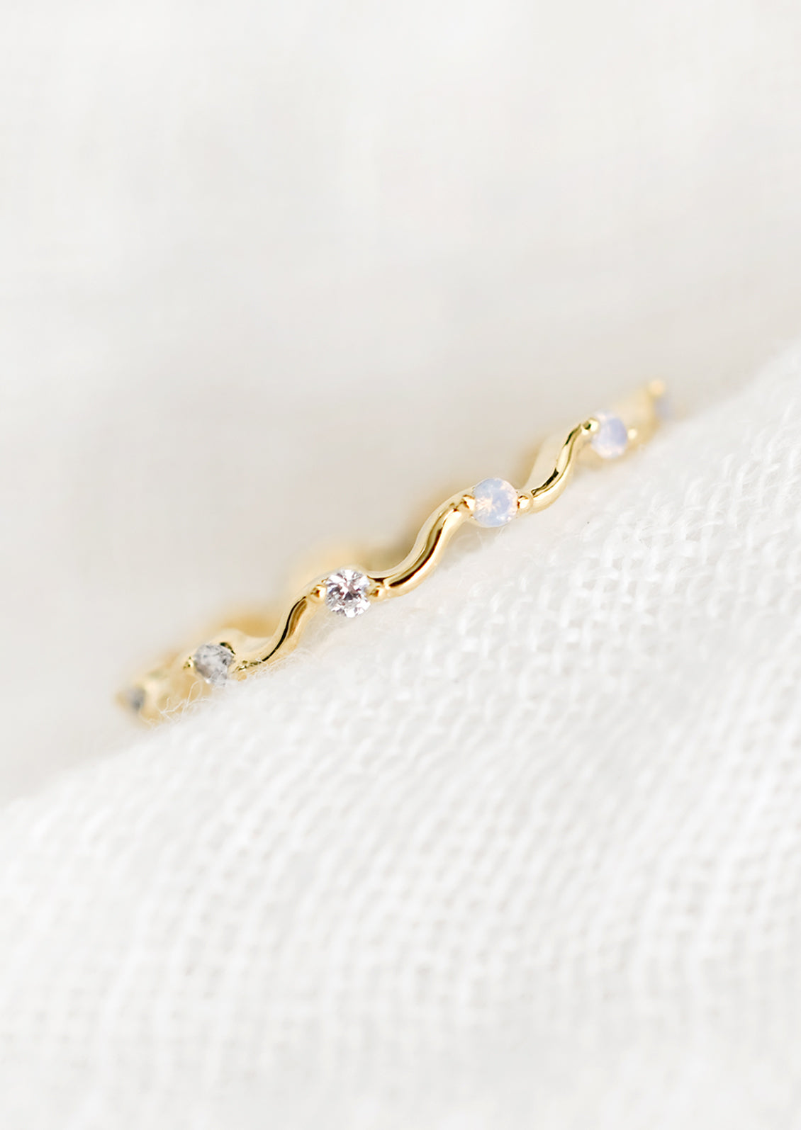 A gold squiggle shaped ring with crystal and opal stones.