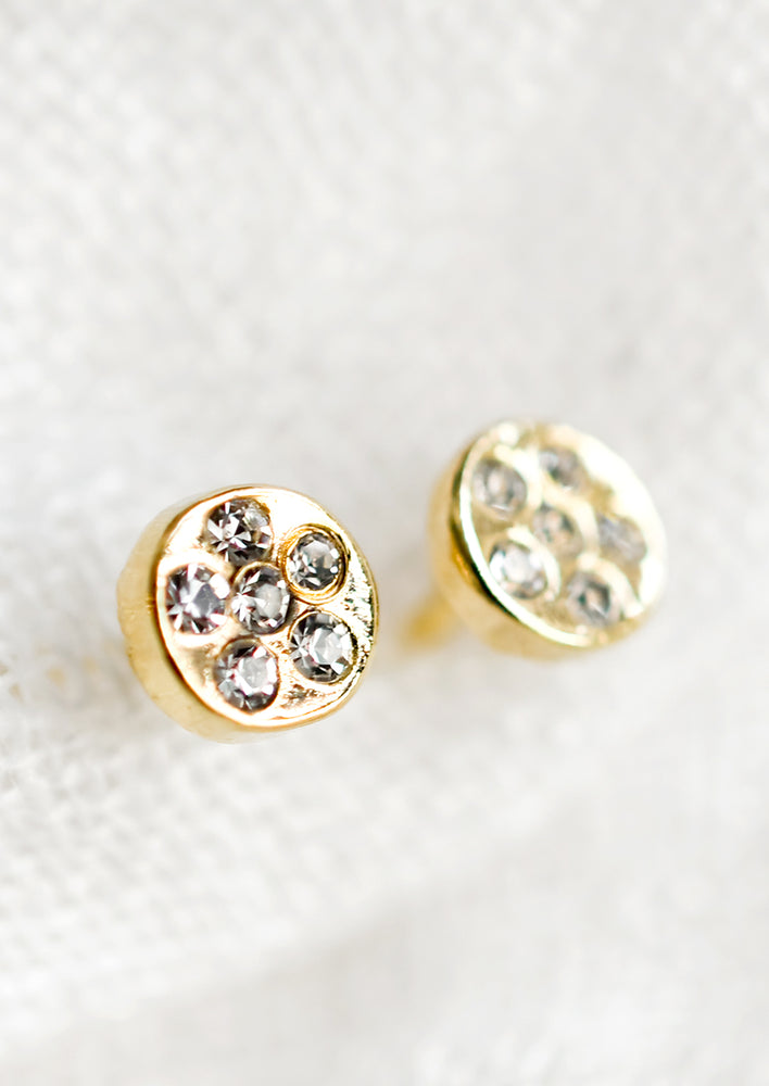 1: A pair of gold circular stud earrings with embedded clear crystals.
