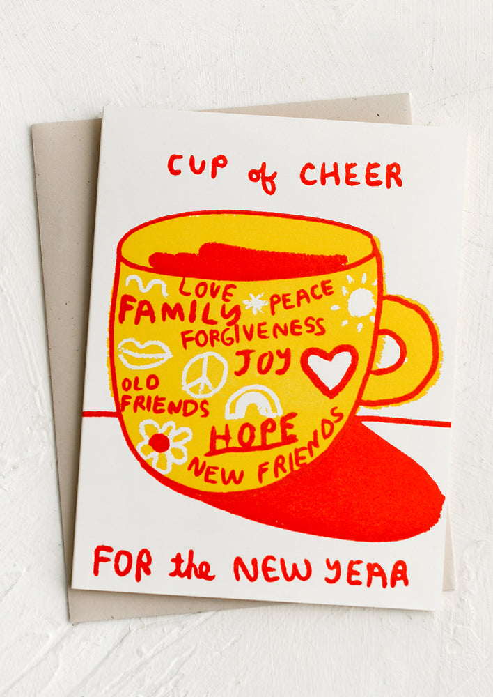 1: A card with hopeful words written on a coffee mug, text reads "A cup of cheer for the new year".