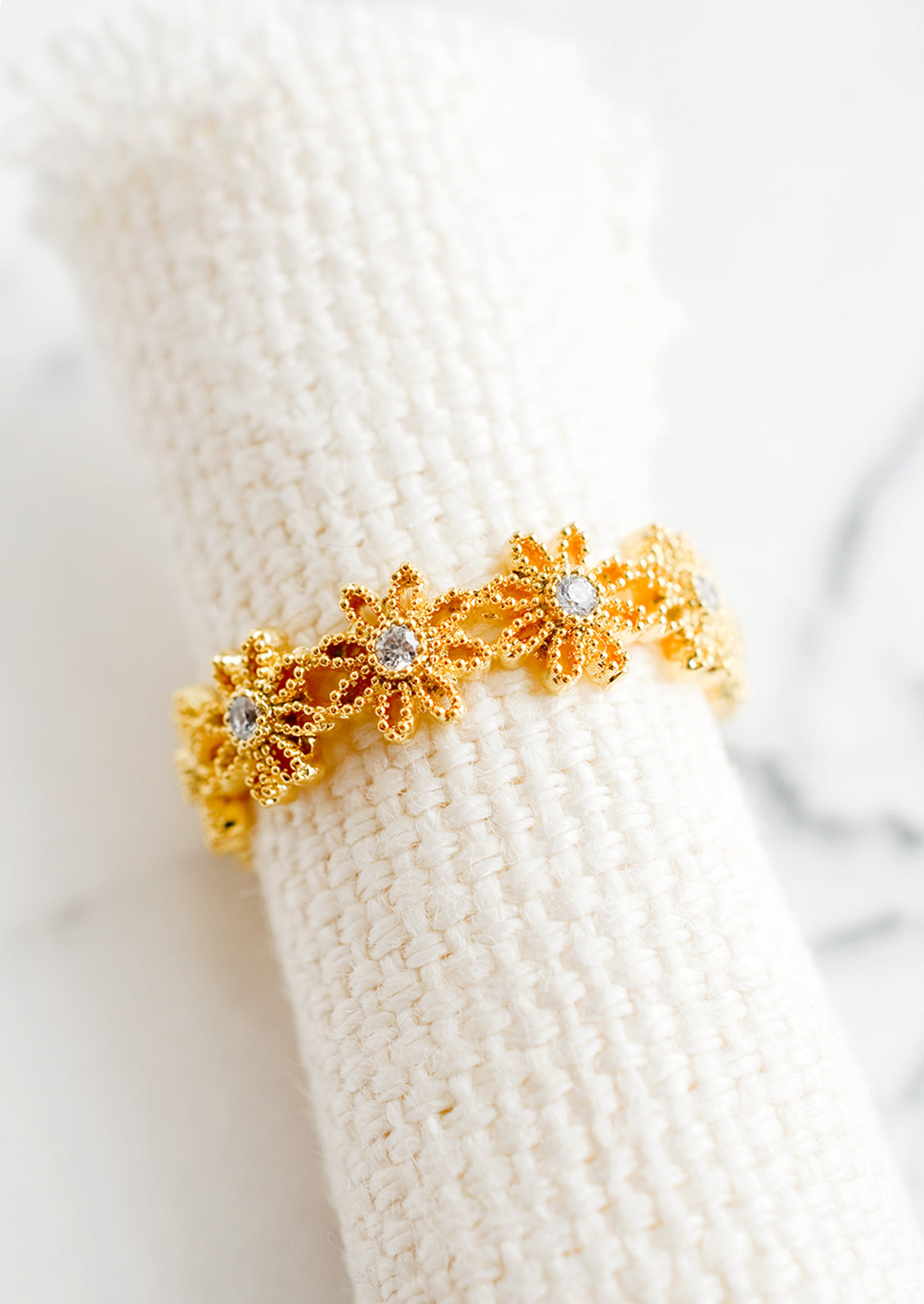 A gold ring made of flower shapes with crystal centers.