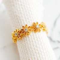 2: A gold ring made of flower shapes with crystal centers.