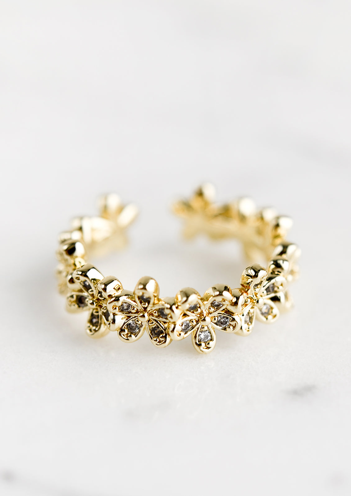 An open-ended ring with continual row of gold flowers with clear crystal detailing.
