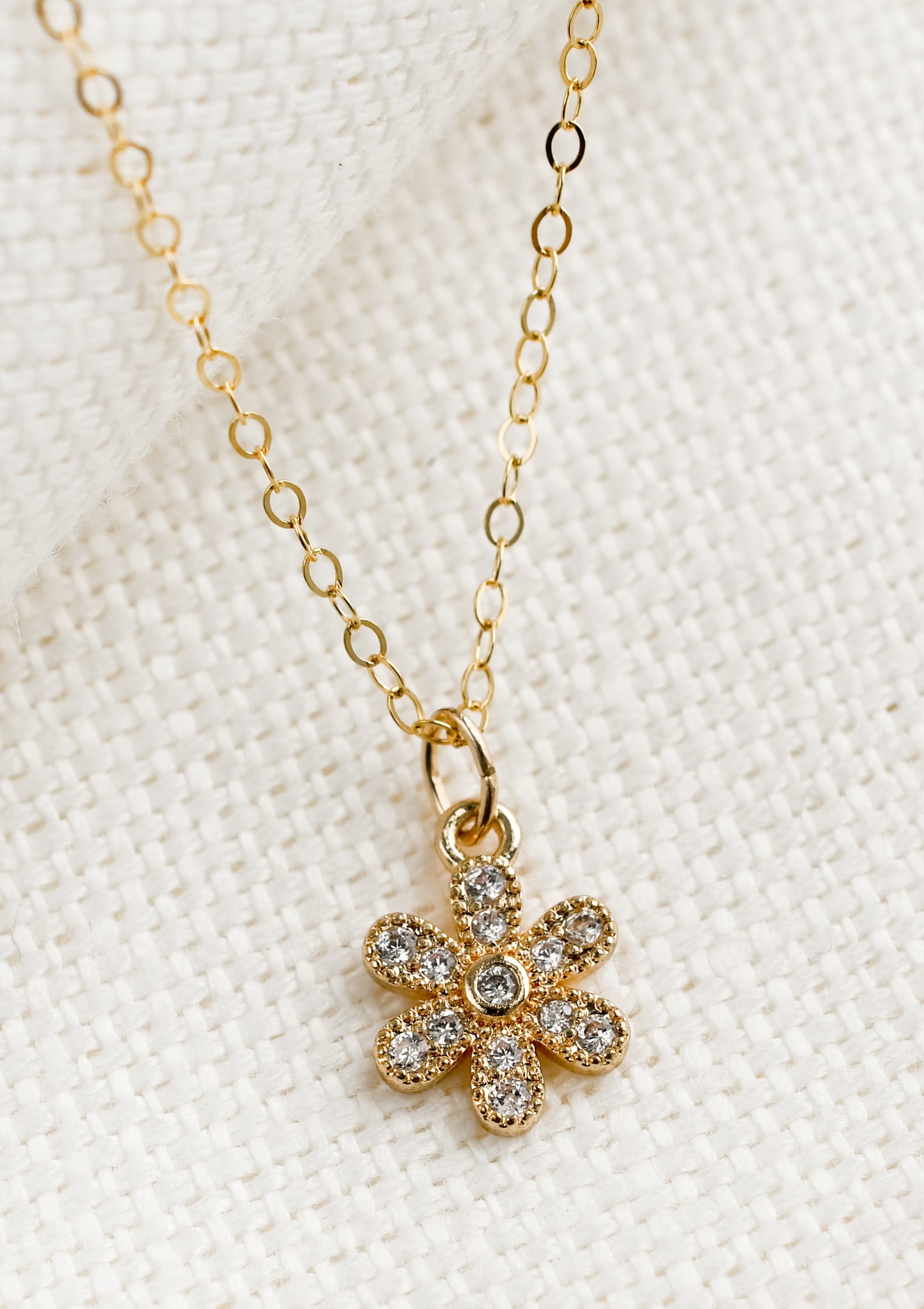 A gold necklace in the shape of a flower with clear crystal detailing.