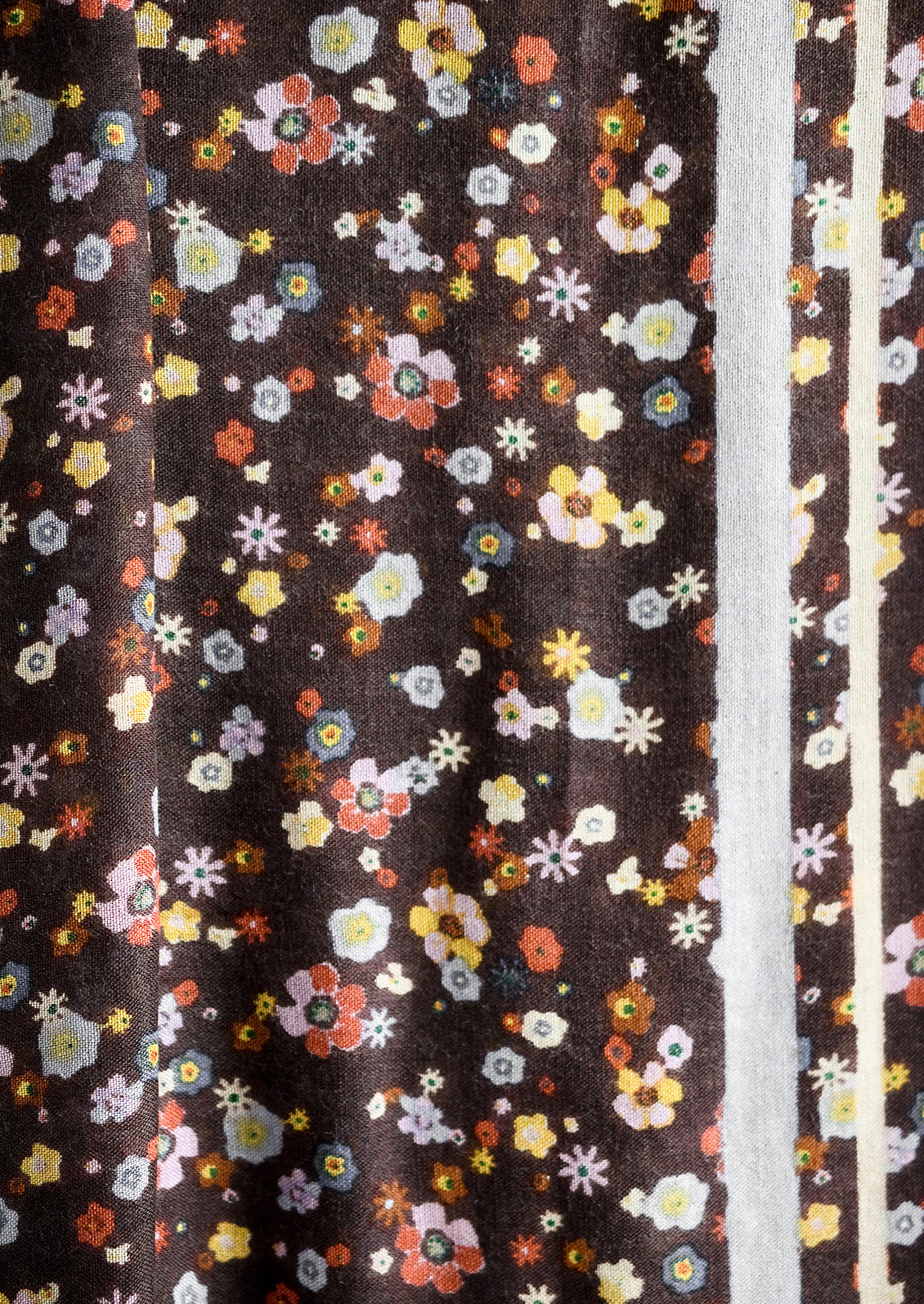 A floral print scarf with brown background and yellow and lilac border.