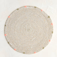 White: A round seagrass placemat in white with grey and pink dashes embroidered around rim.