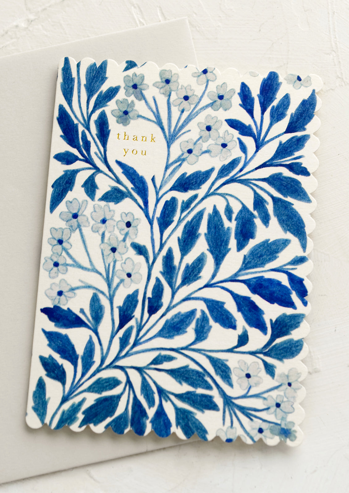 A blue floral print greeting card reading "thank you" in gold letters.