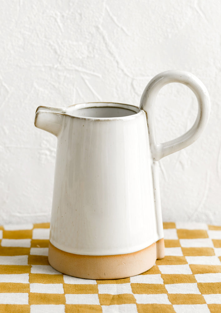 1: A white ceramic pitcher with exaggerated handle.