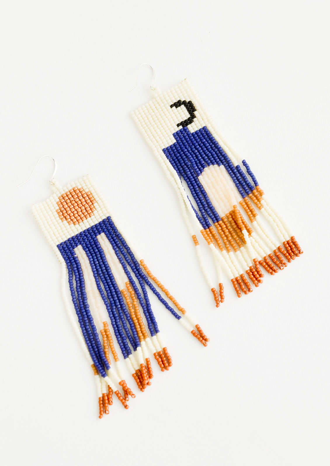 Fringe earrings of cream, blue, orange, and black beads depicting abstract scenes of the sun and moon.
