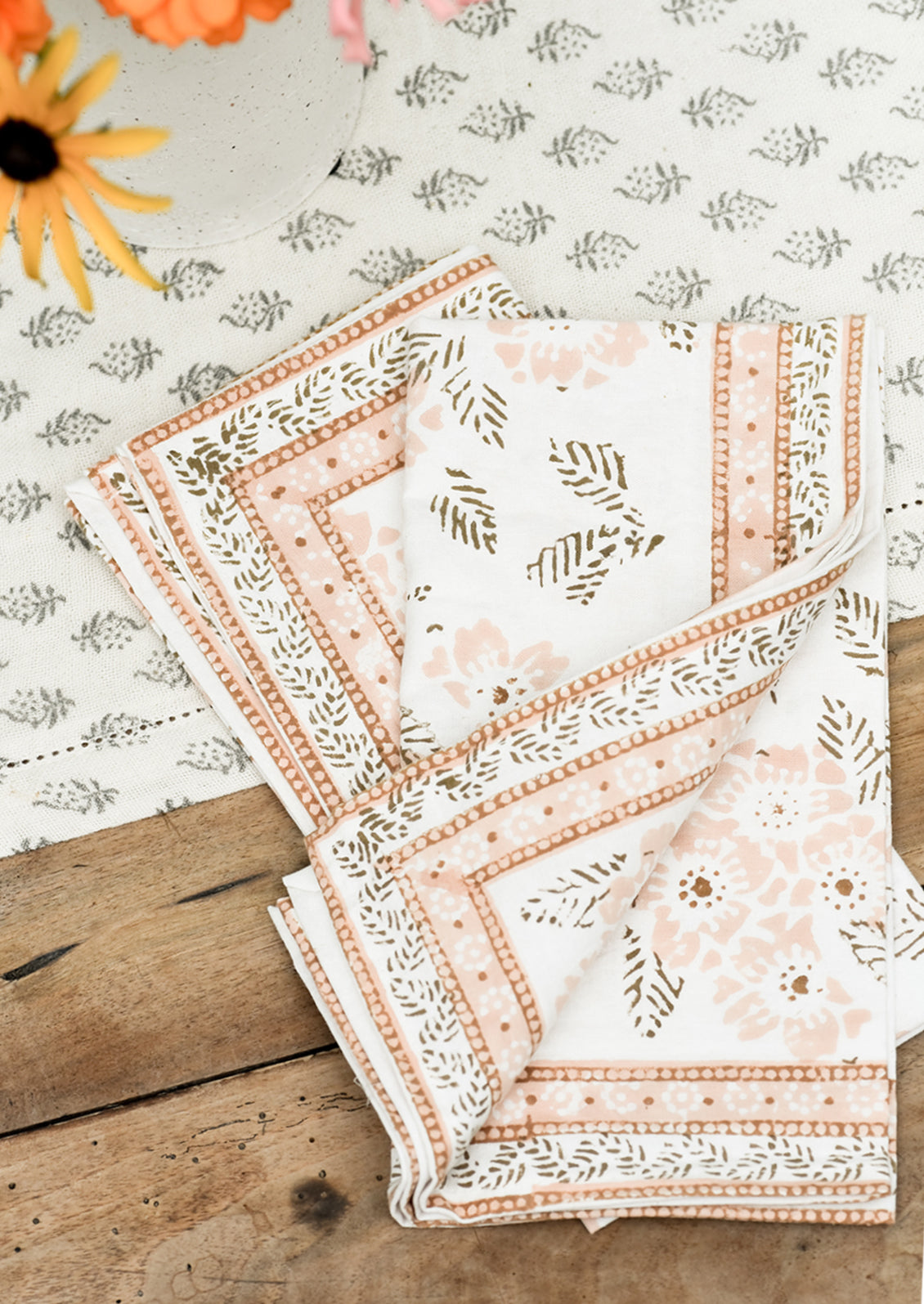 A pair of cotton napkins with peach and brown floral print.