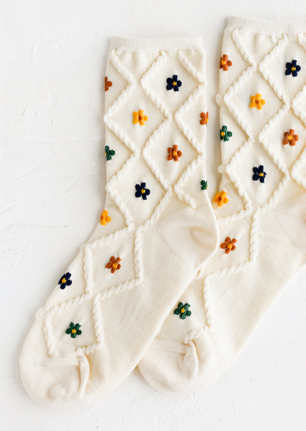 Cream Multi: A pair of cream socks with diamond pattern and florals.