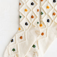 Cream Multi: A pair of cream socks with diamond pattern and florals.