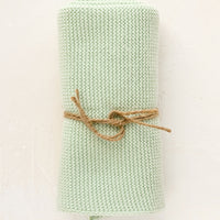 Mint: A knit cotton dish towel in mint, rolled and tied with twine.