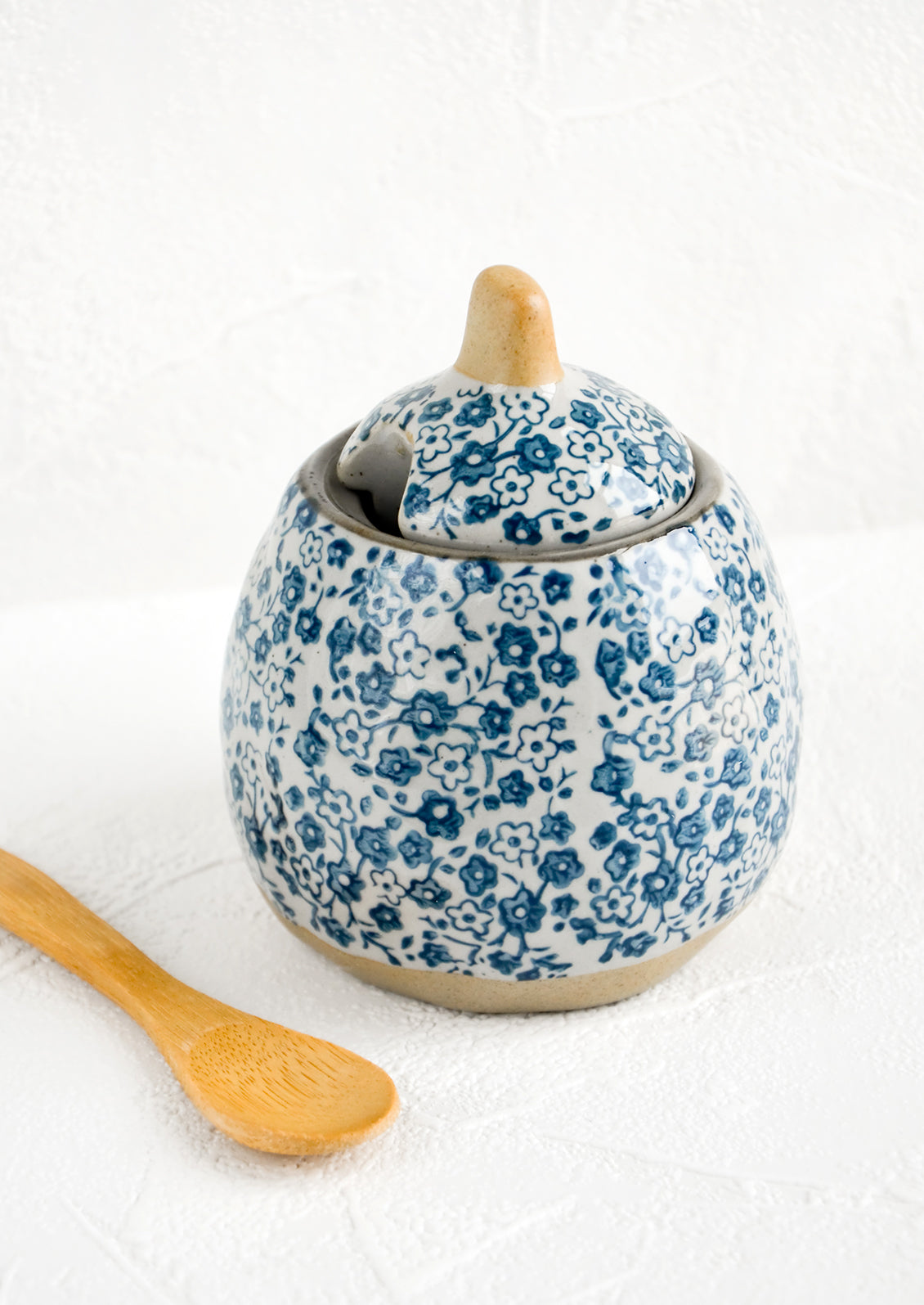 A blue floral ceramic sugar pot with wooden spoon
