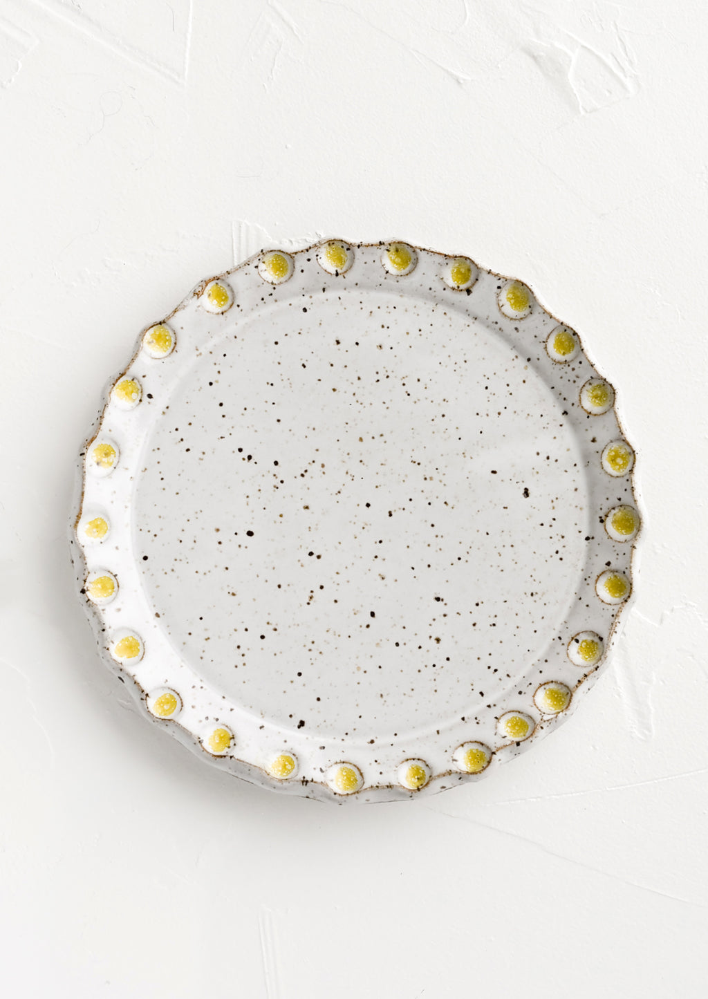Glossy White Speckle / Yellow: A round ceramic plate with yellow dot print detail.