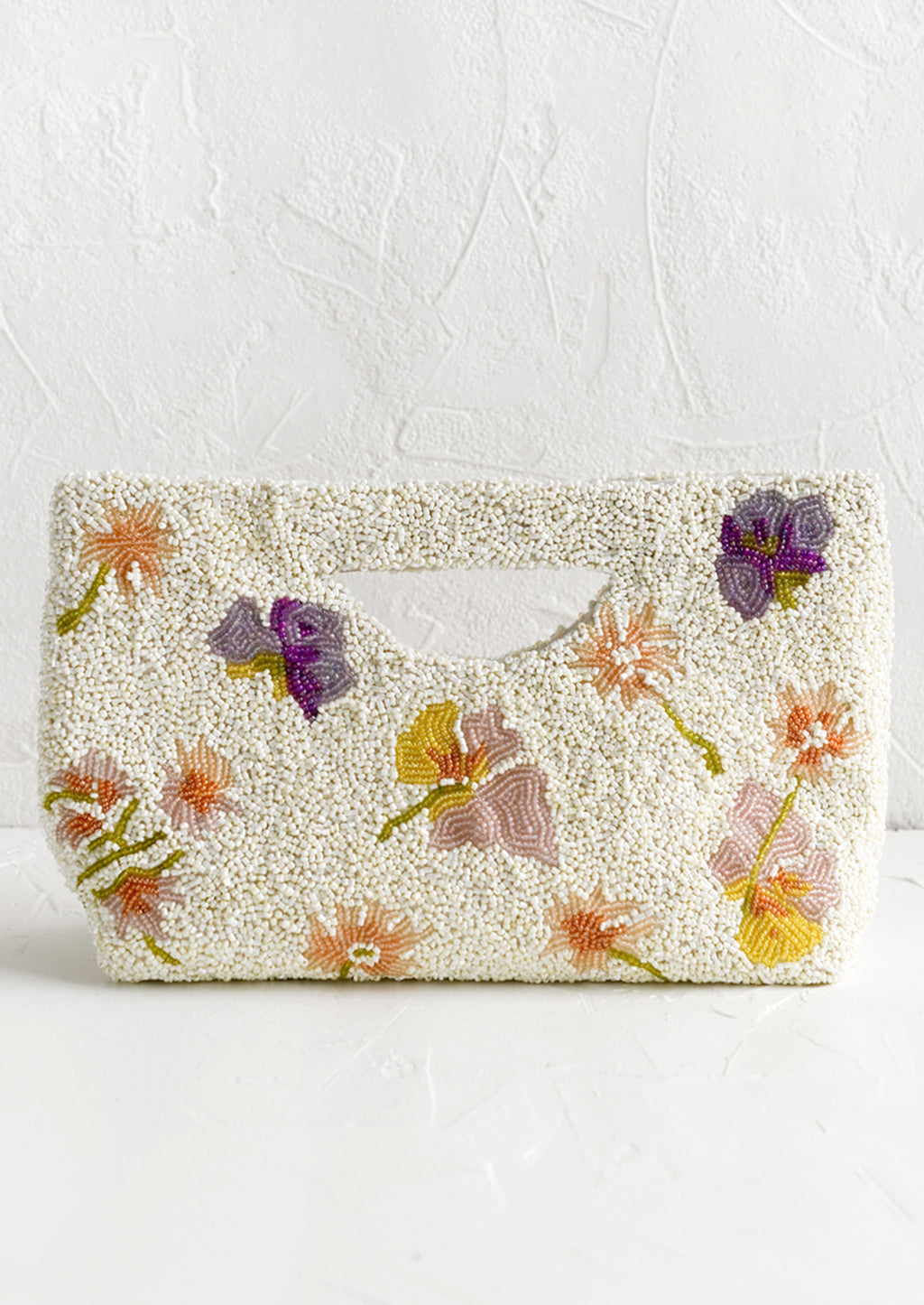 1: A white beaded east-west clutch with cutout handle and pastel floral pattern.