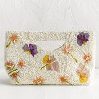 1: A white beaded east-west clutch with cutout handle and pastel floral pattern.