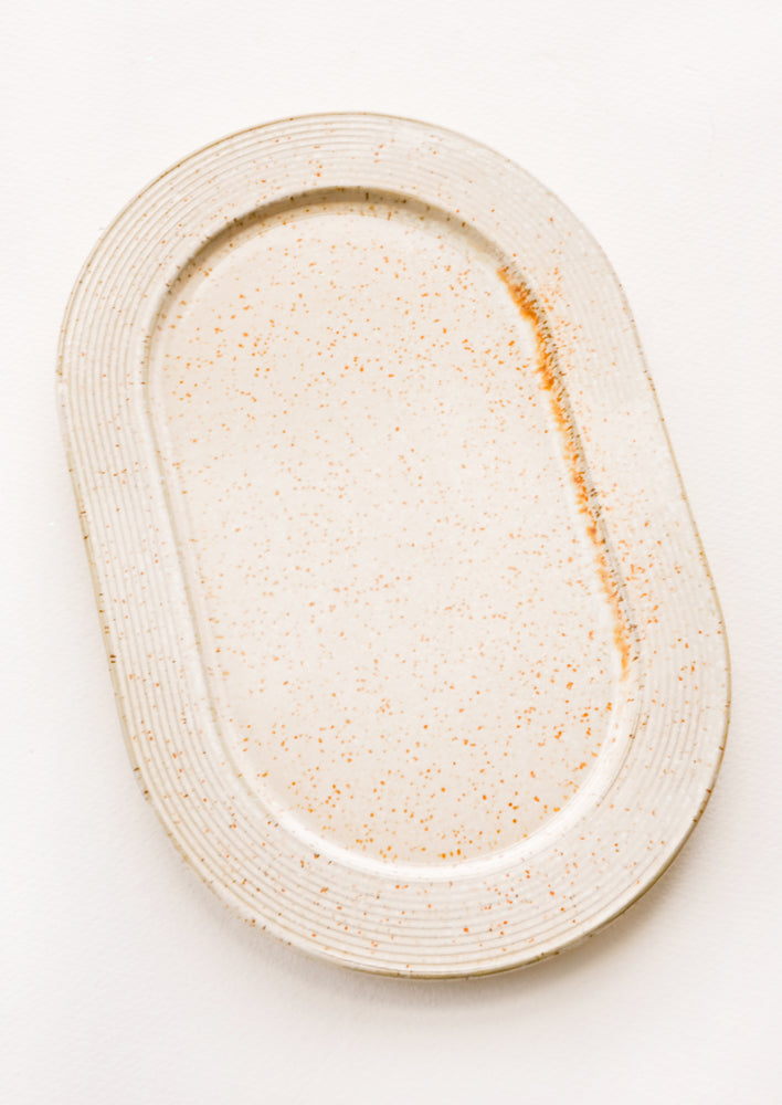 1: Tan ceramic oval tray with brown speckles and raised rim.