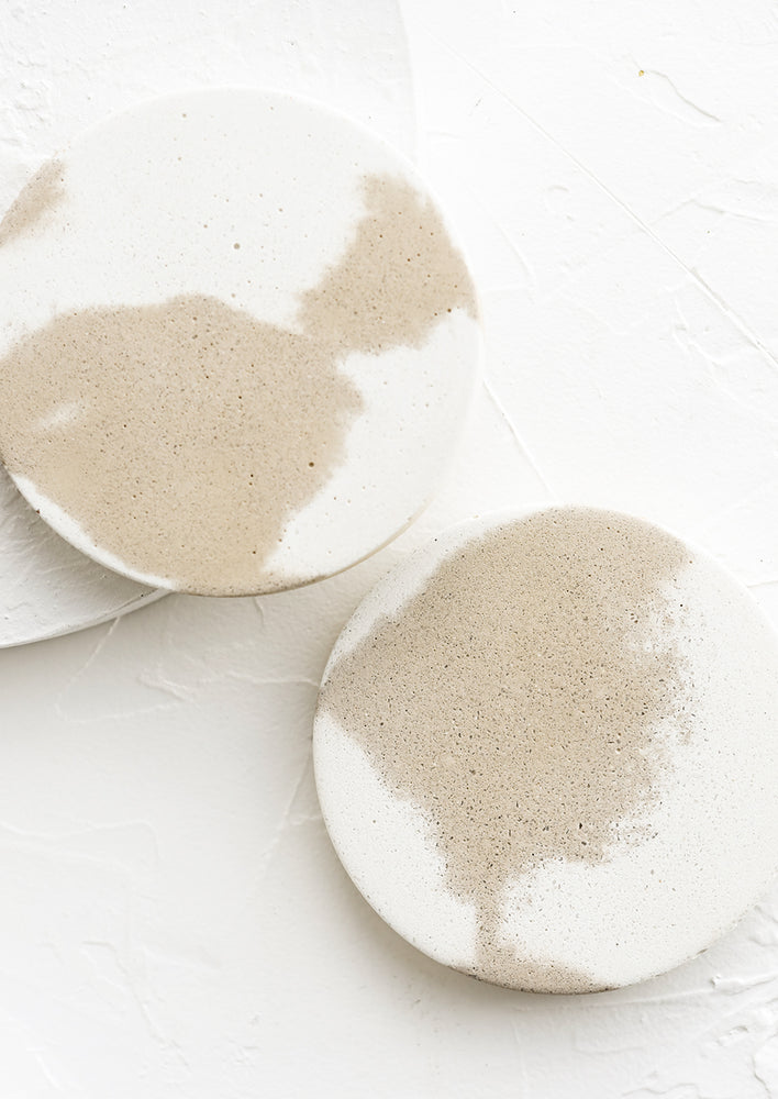 A pair of coasters in white and tan marble.