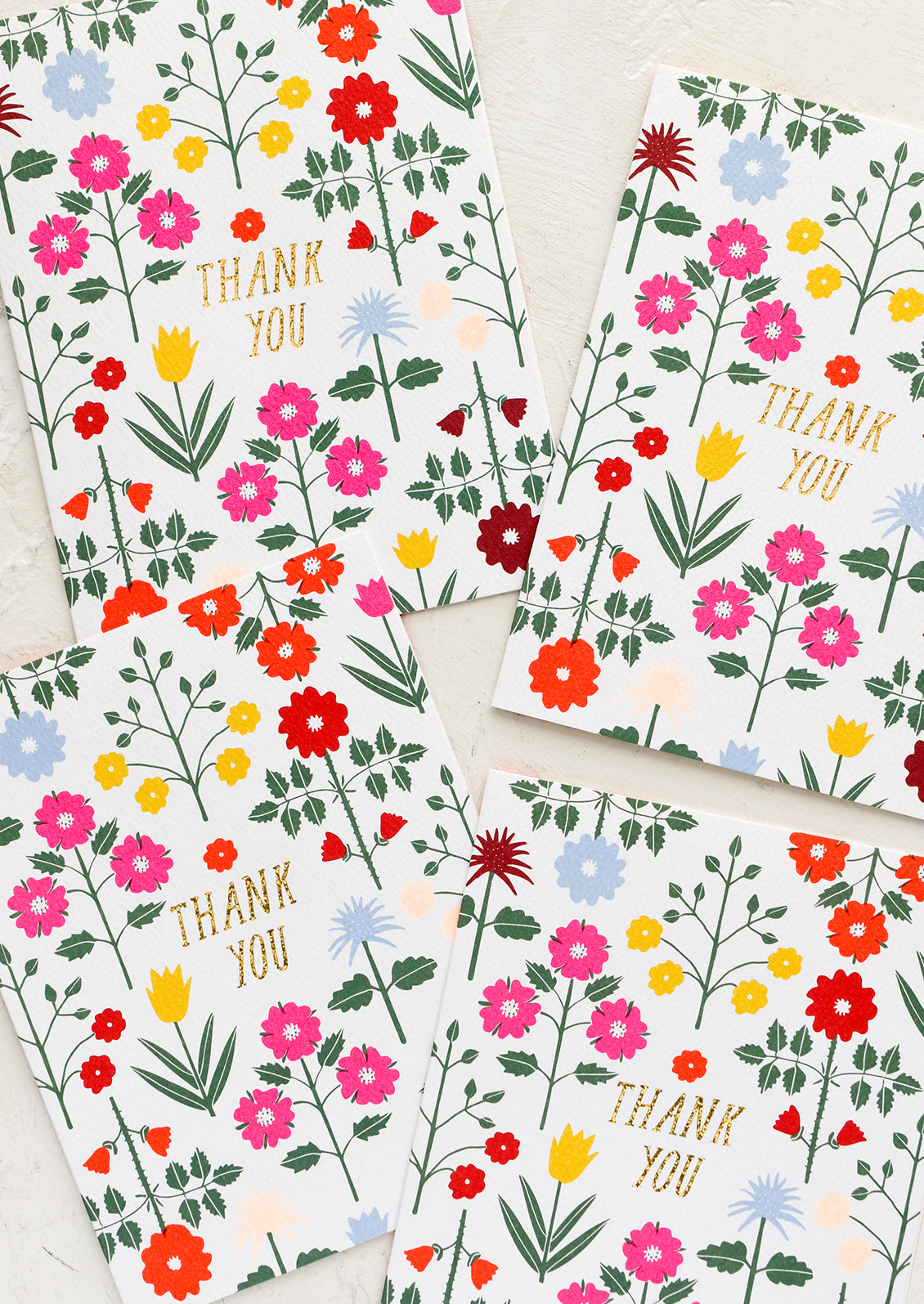 A set of thank you cards with vibrant floral pattern and gold "Thank You" text at center.