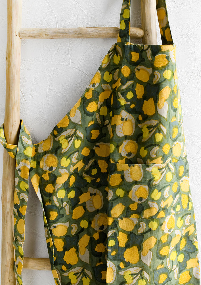 1: A printed apron in green, orange and yellow fruit print.