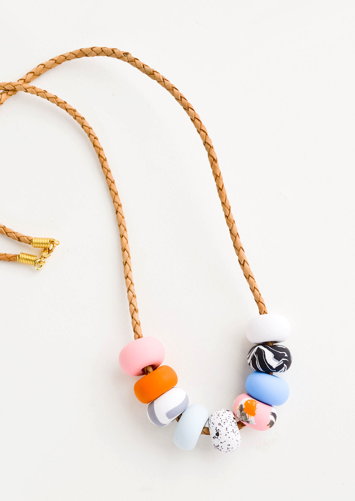 Necklace featuring colorful patterned clay beads on braided leather cord