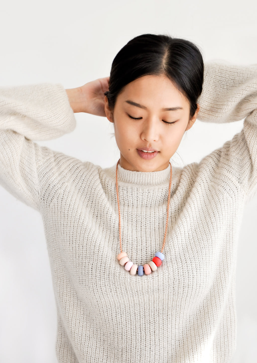 3: Model wears clay bead necklace and ivory sweater.