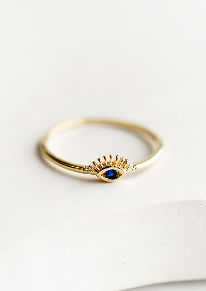 A gold ring with evil eye design with blue stone.