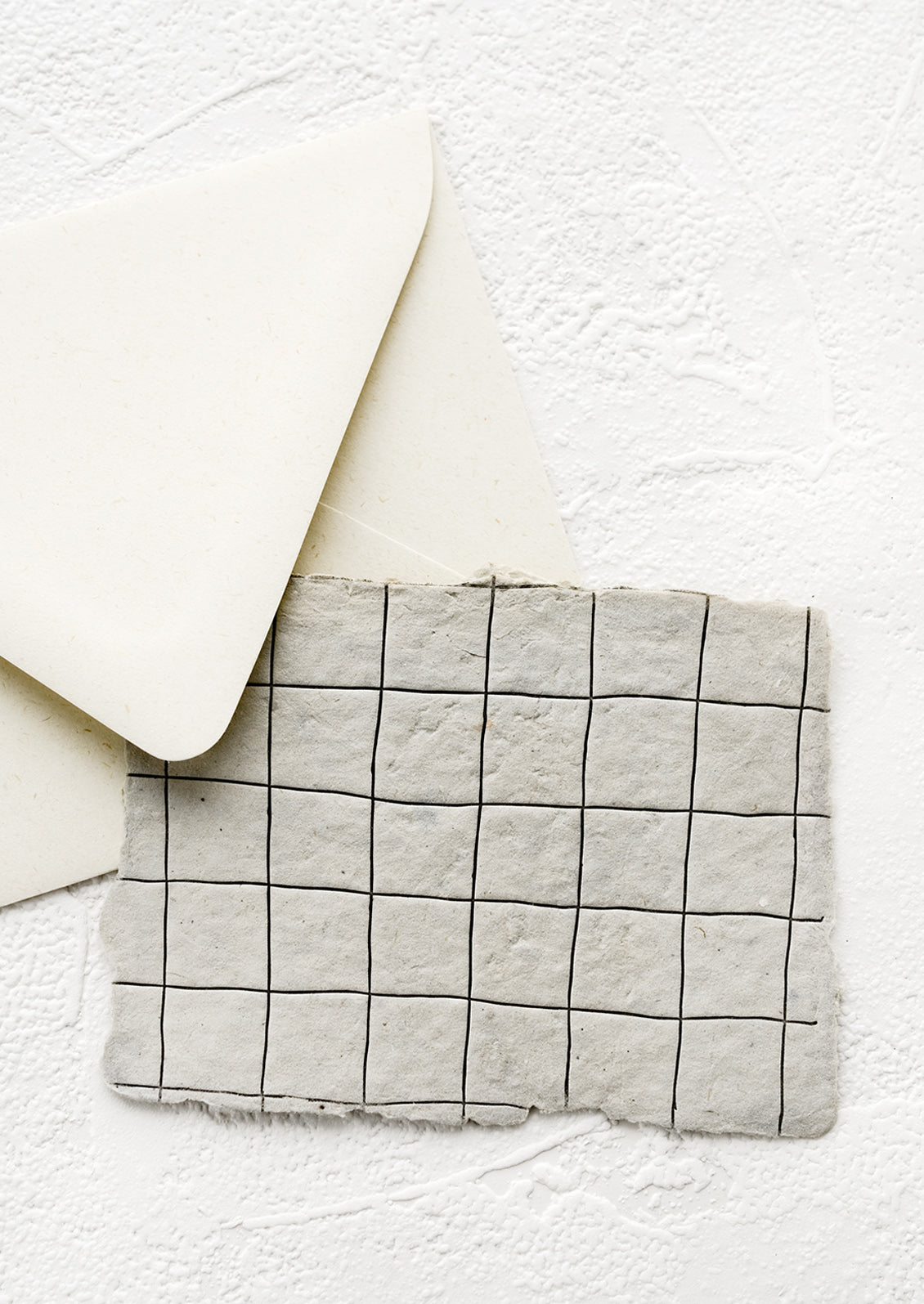 A greeting card made from handmade paper with a letterpress printed grid pattern.