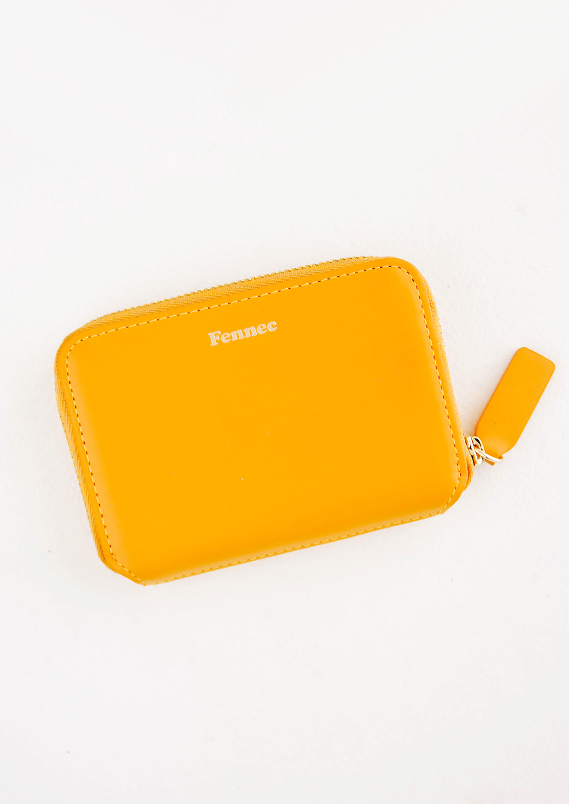 Small orange leather zip wallet with Fennec embossed in small gold letters at top of wallet face.