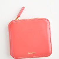 Light Brick: Light red leather wallet that zips on three sides, with matching tab pull.
